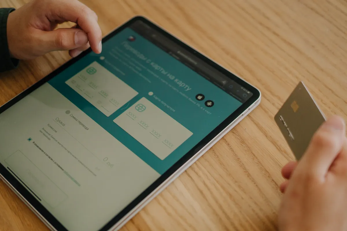 Manos pagando una compra en línea con una tablet y una tarjeta