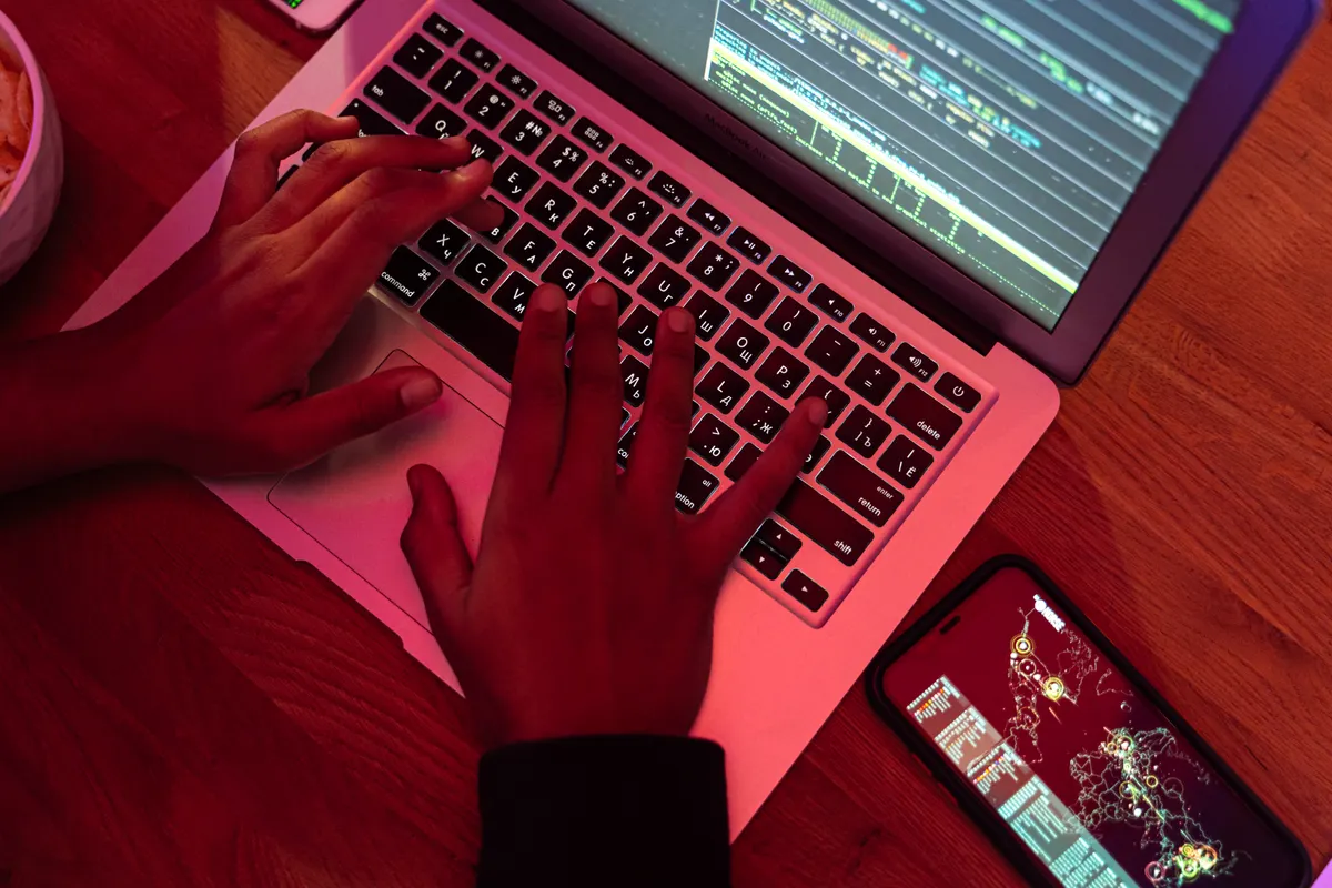 Manos escribiendo código en una laptop de noche