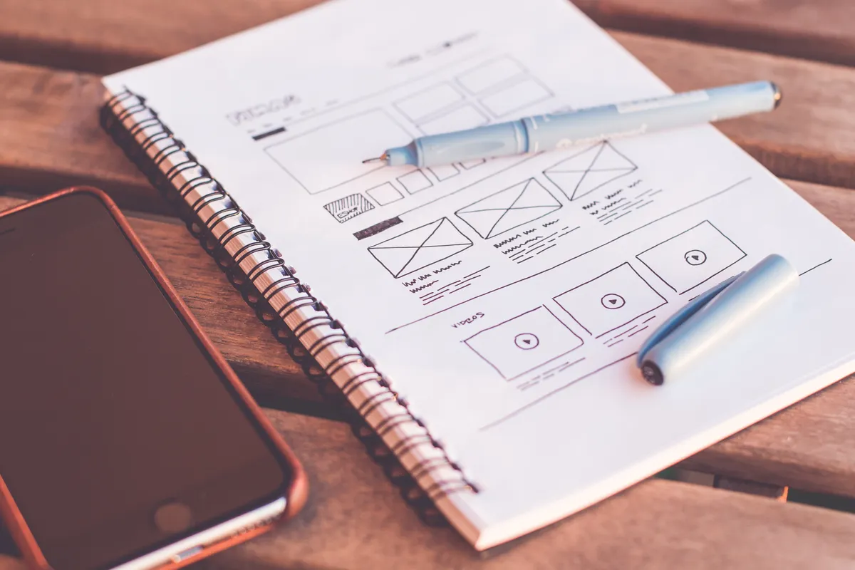 Cuaderno con wireframes junto a un celular